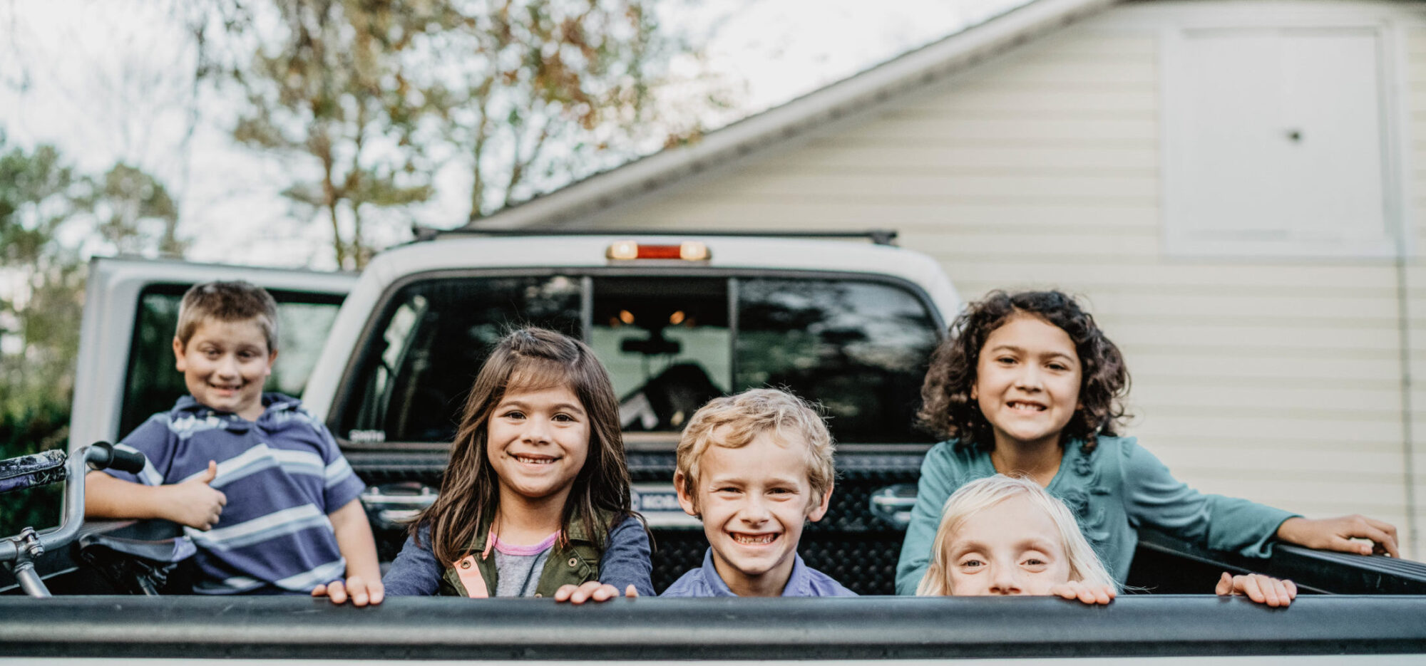 Smiling foster children in the back of a truck.