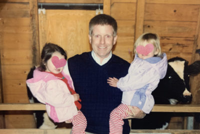 A man symbolizing why foster children by smiling and holding two foster girls.