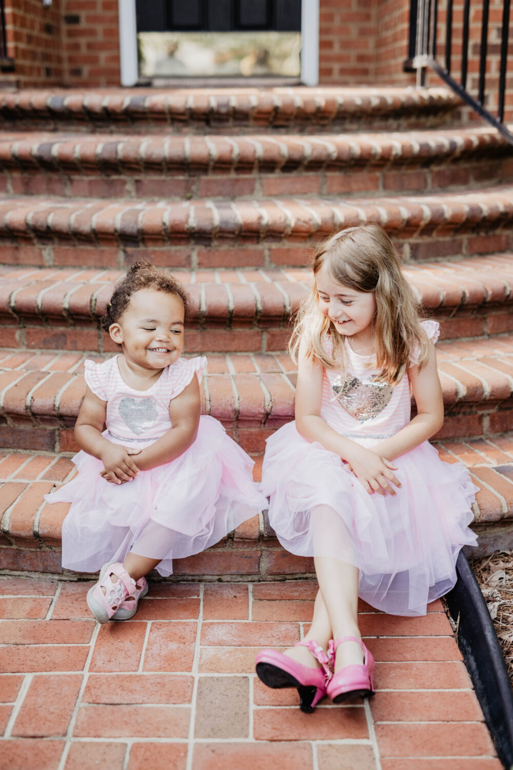 Two girls sitting on brick stairs smiling