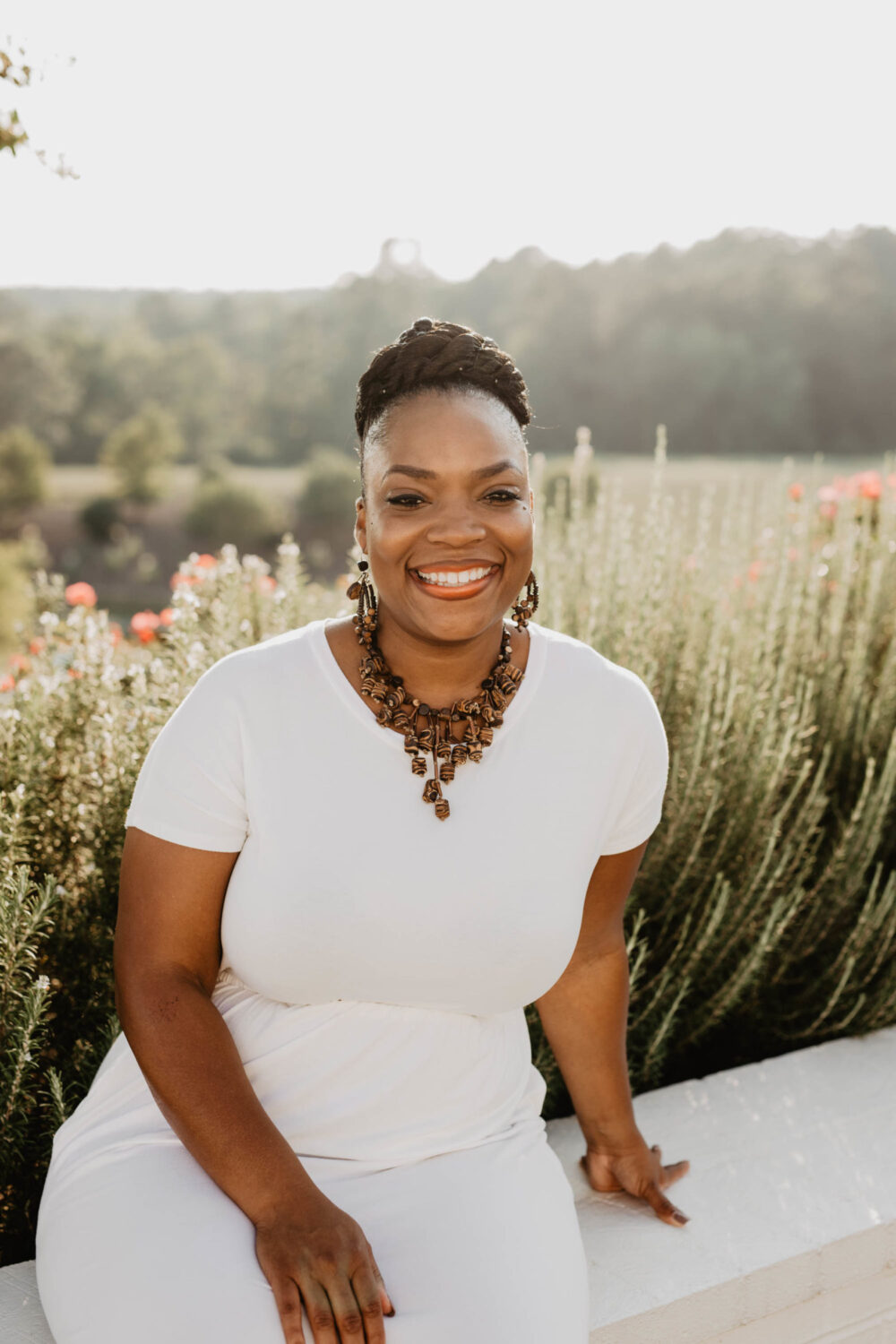 A woman sitting on a white ledge with nature in the background