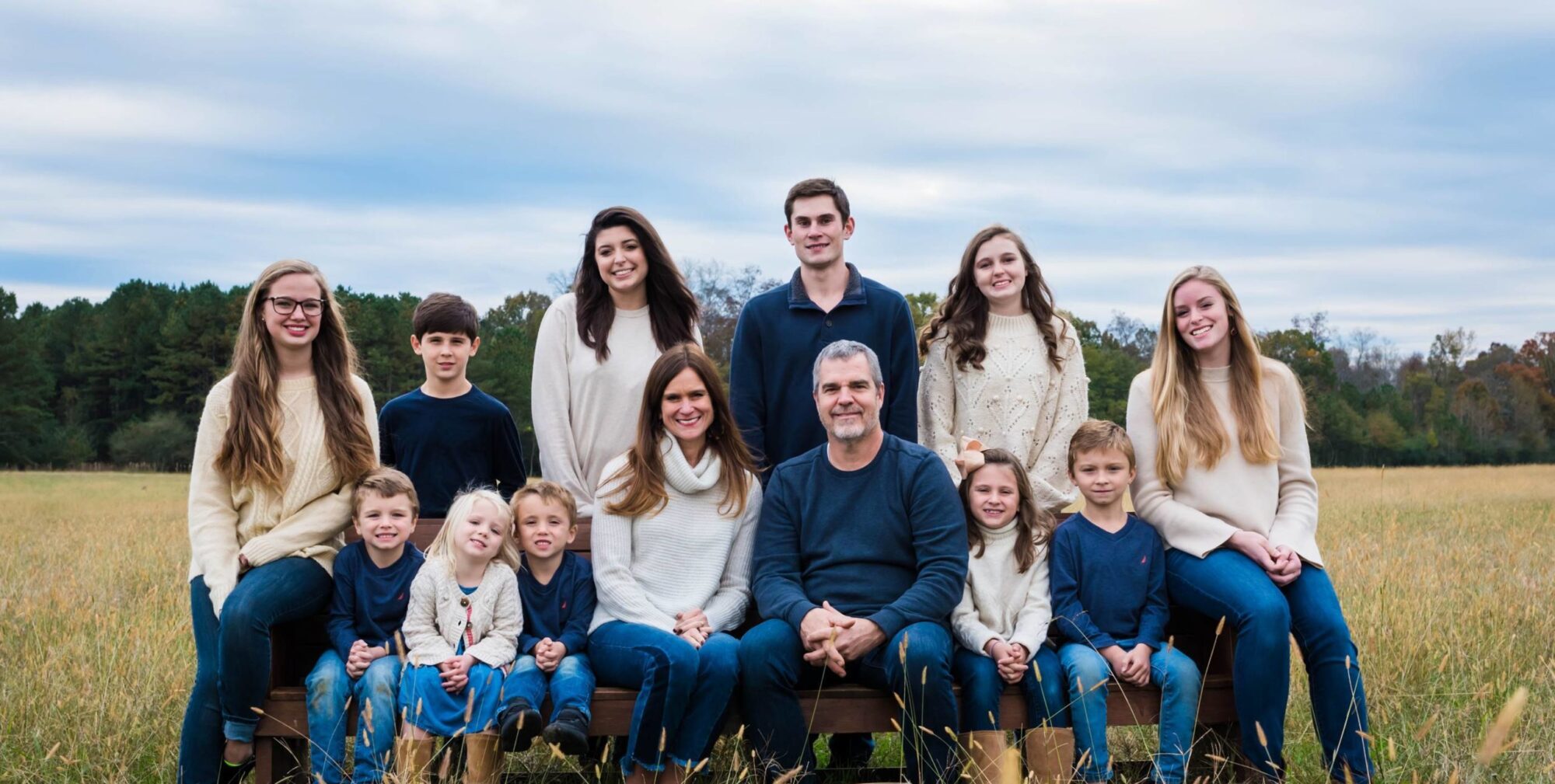 Foster house parents in a field with a diverse range of kids