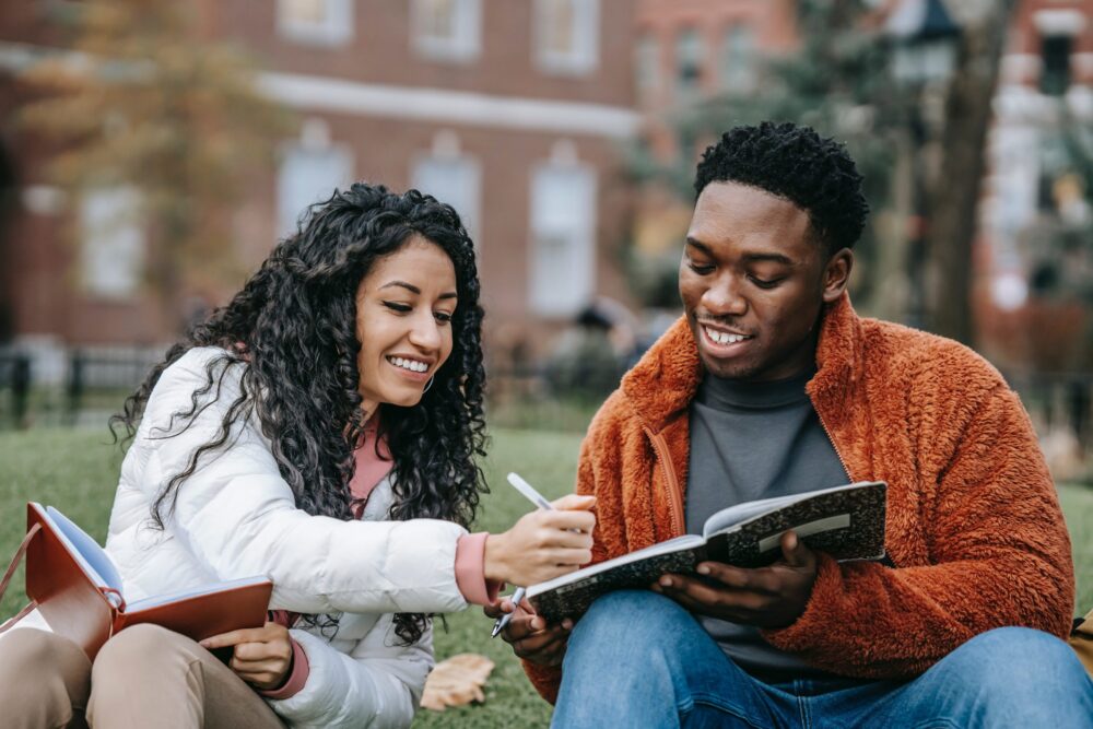 Two young adults happily studying outside a college campus.