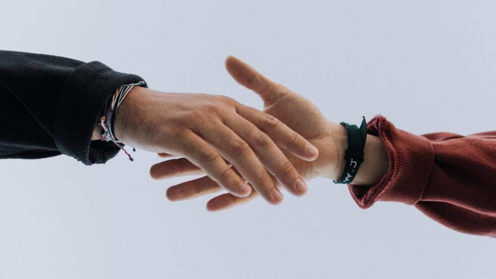 Two male hands reaching out towards each other with a blank background.