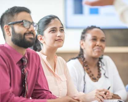 Three adults grinning while looking forward